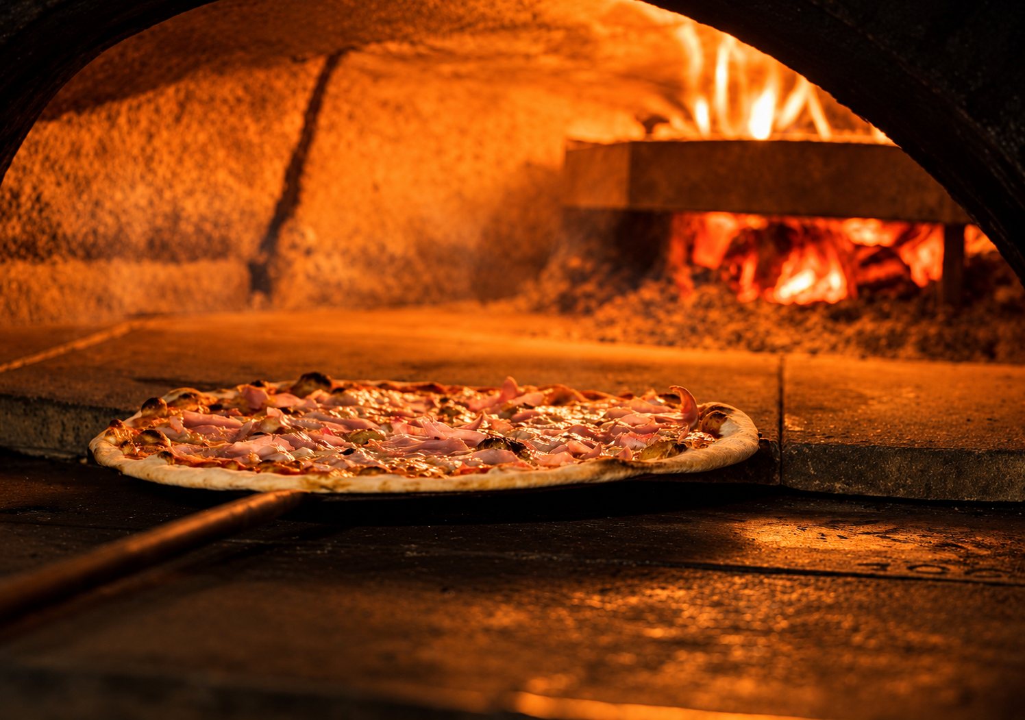 Pizza sur la pelle à l’entrée d’un four, braises au fond
